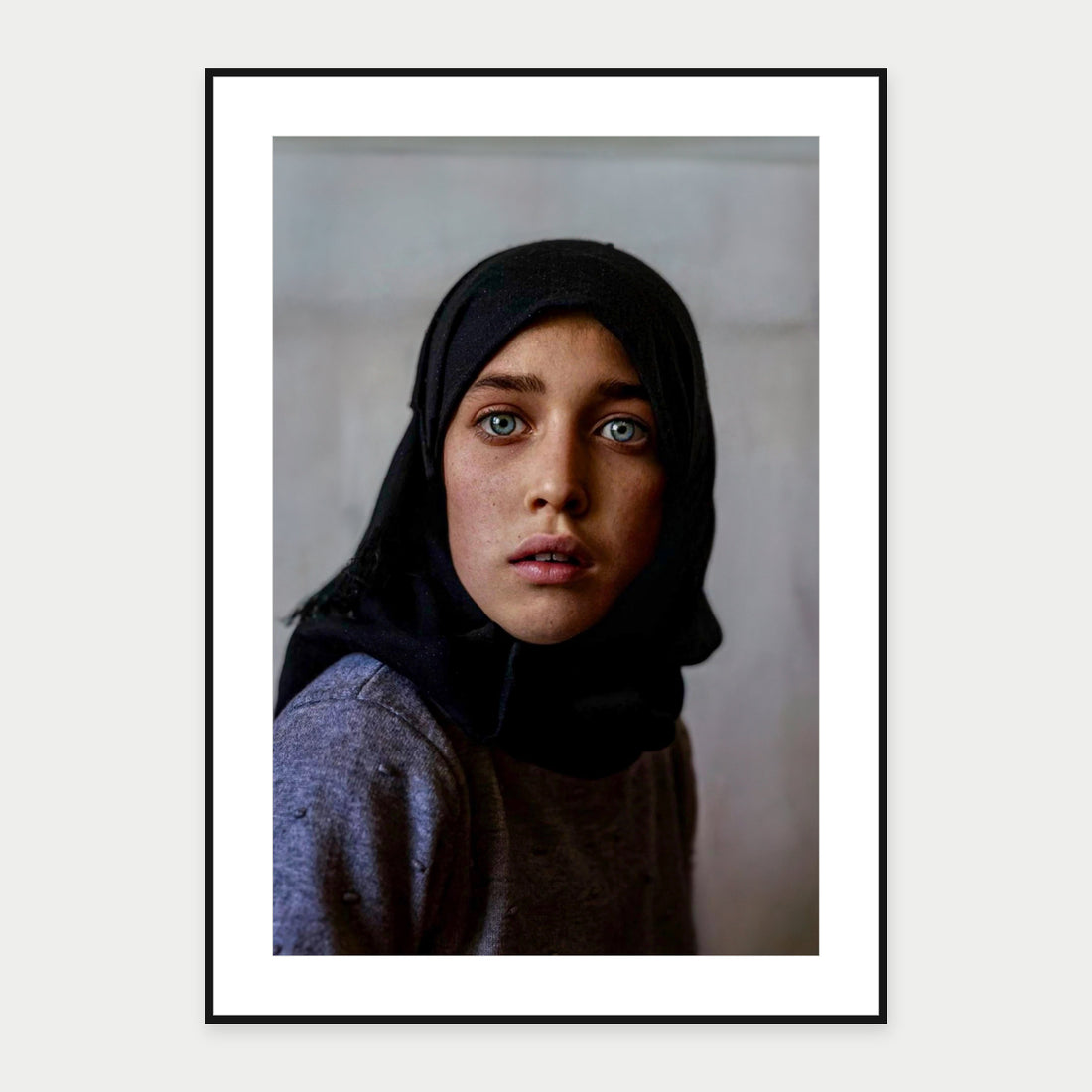 Black-framed display mockup of Afghan Girl I by Laurin Strele; frame shown for illustration.