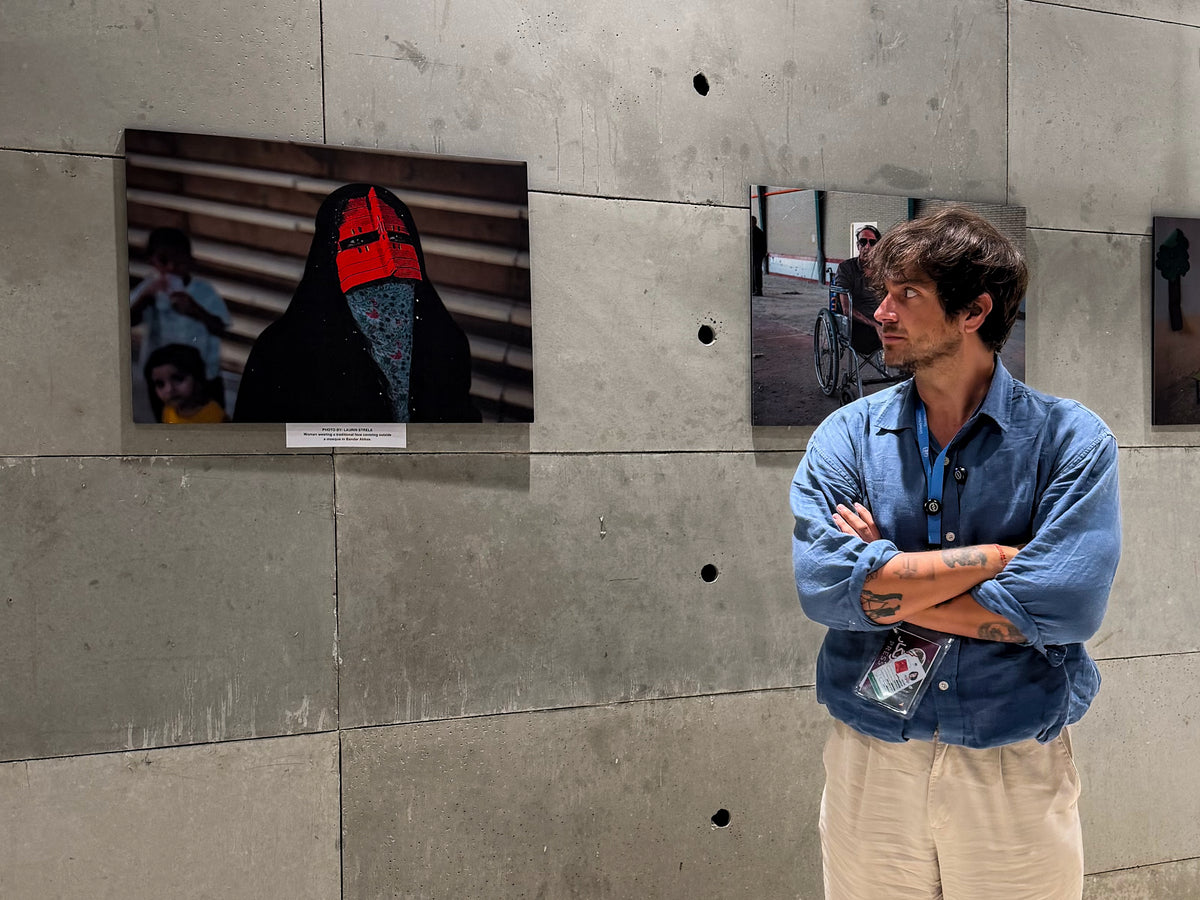 Laurin Strele beside documentary photographs displayed on a concrete wall.