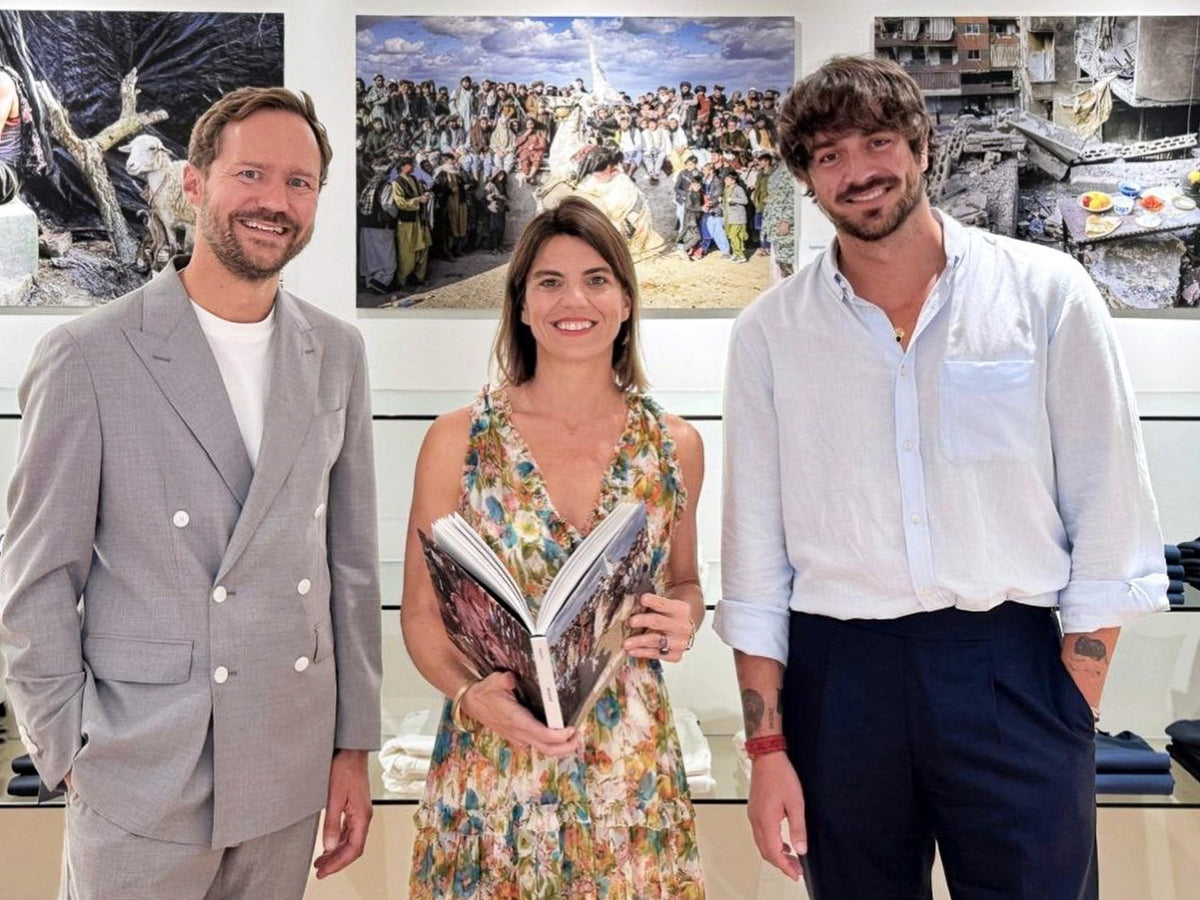 Laurin Strele with two visitors in front of documentary photographs.