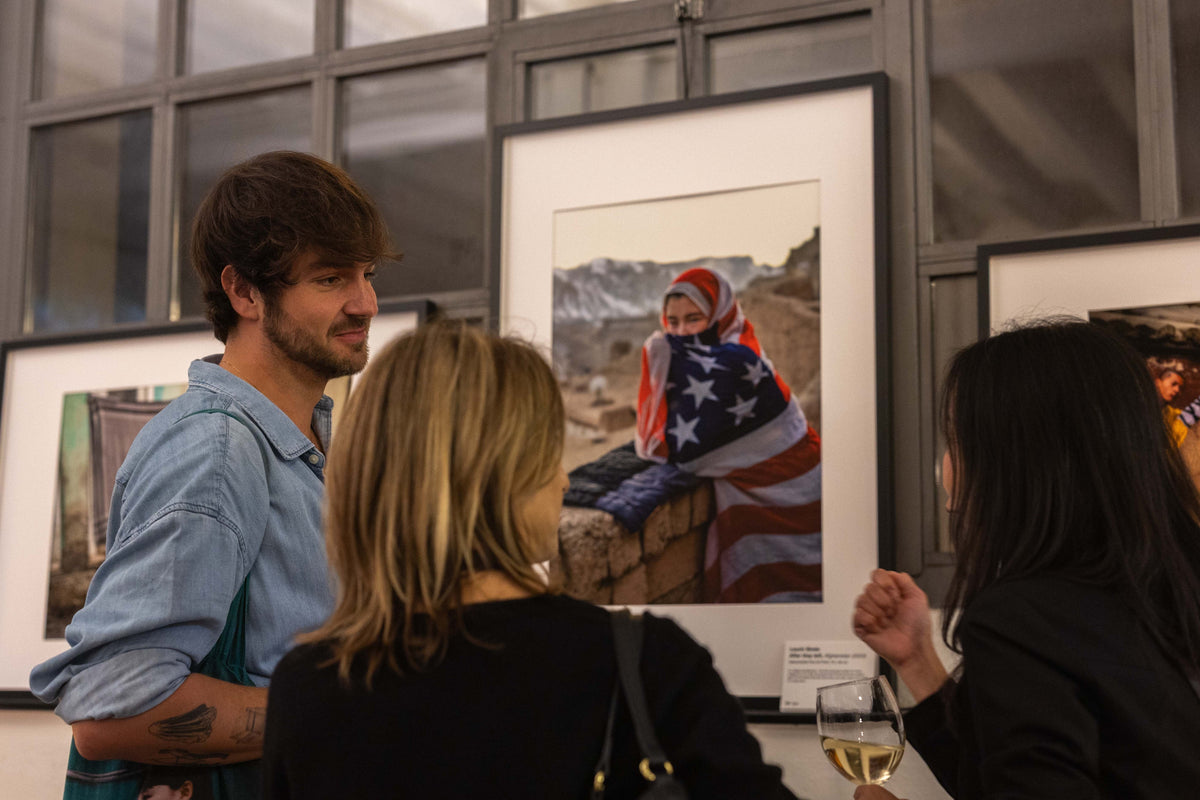 Conversations beside framed documentary photographs at an exhibition.