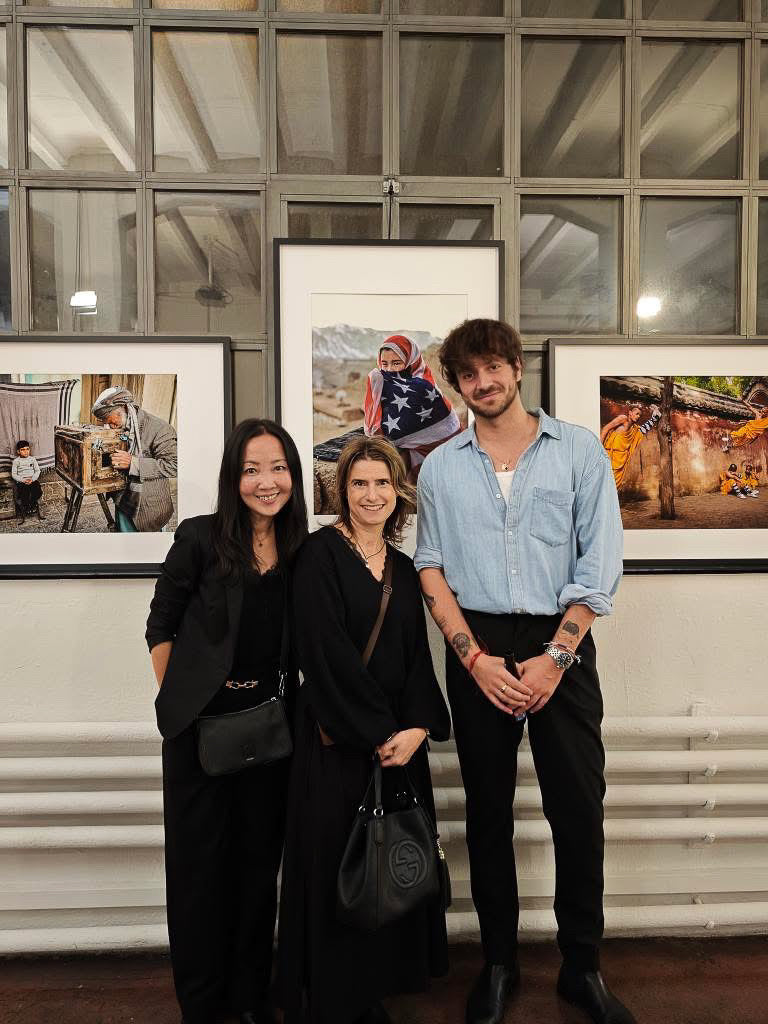 Laurin Strele and two visitors standing beside framed documentary photographs.