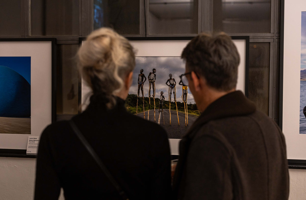 Visitors viewing framed photographs at an exhibition of Laurin Strele’s work.