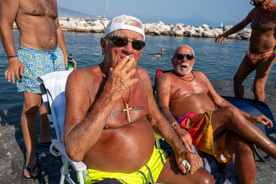 A1 poster of men relaxing beside the sea in Naples, Italy, by Laurin Strele, with a white border and light-grey artist name.