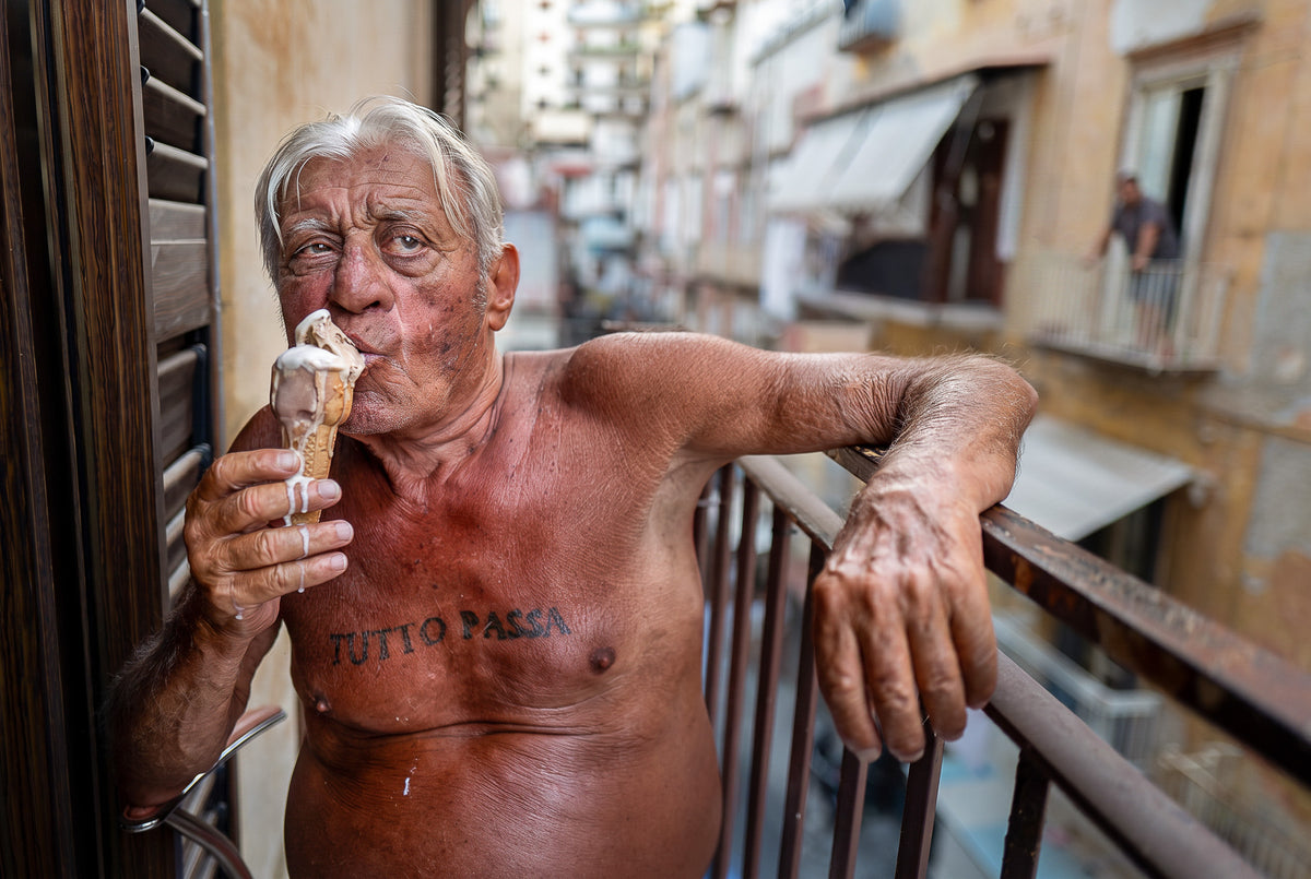 Antonio eats an ice cream on his balcony in Naples, Italy, with a Tutto Passa tattoo across his chest. Photograph by Laurin Strele.
