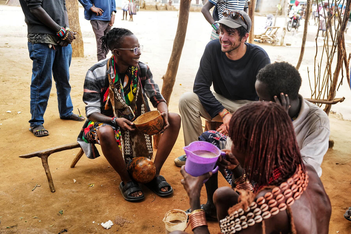 Workshop participants share a conversation outdoors, holding bowls and cups.