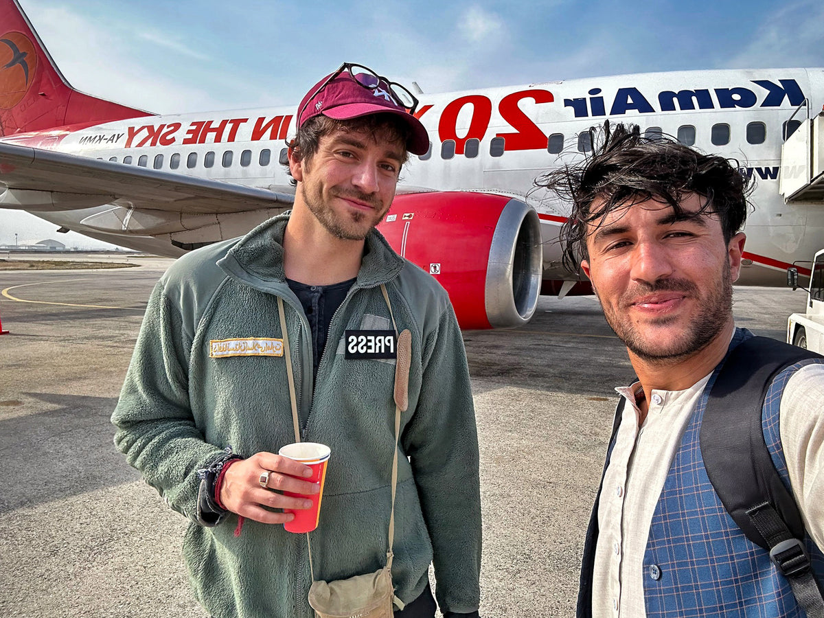 Two travellers beside a passenger aircraft on the way to a workshop.