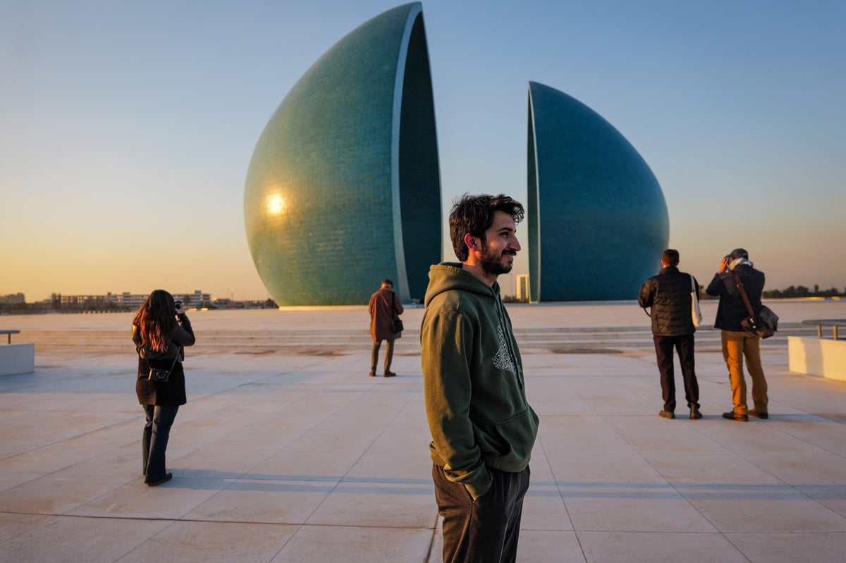 Fotografen auf einem sonnigen Platz vor einem großen türkisfarbenen Denkmal.