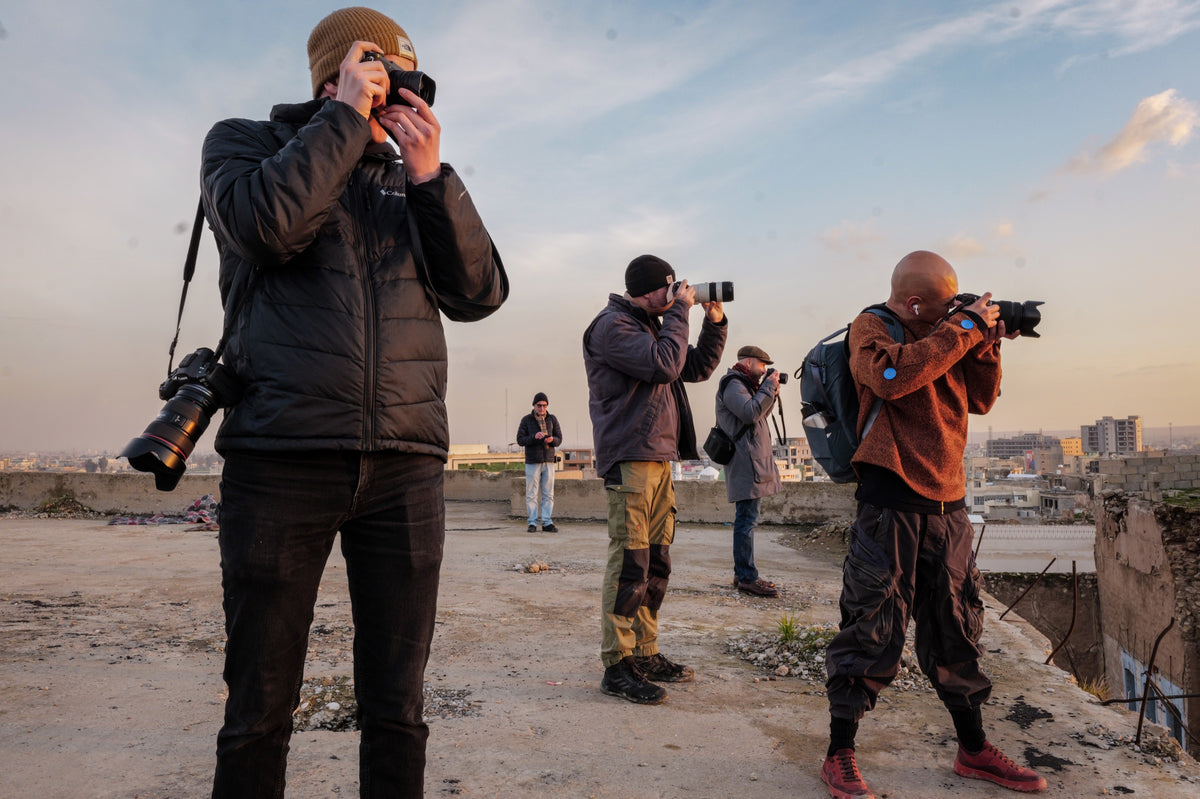 A group of photographers working on a rooftop in the evening light.
